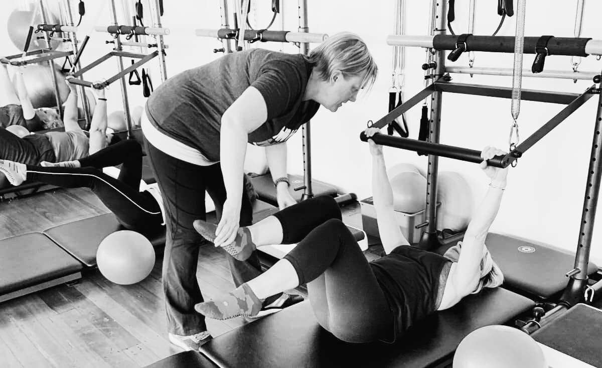 Meet the Team 2 instructor adjusting a woman in a neuro pilates class