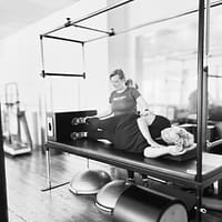 woman adjusting a client in a pilates class