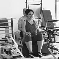 smiling woman doing a beginners reformer pilates class