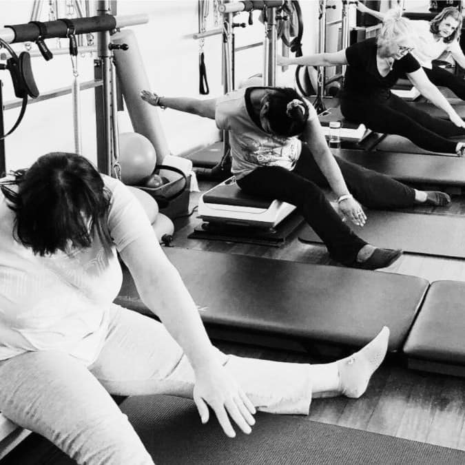 TWR - Tower Pilates 1 women doing a stretch on the hypervibes in a tower pilates class