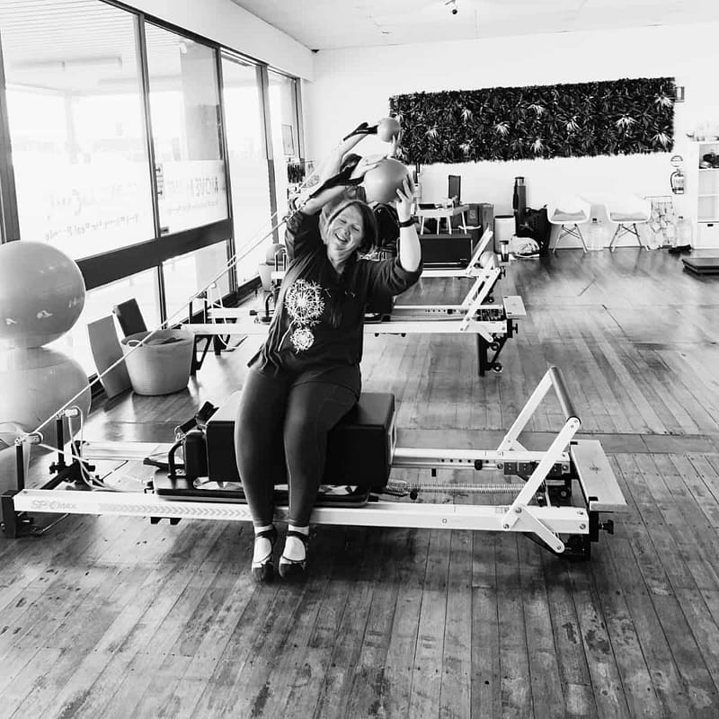 smiling woman doing a sidebend on the pilates reformer