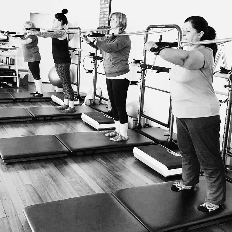 women doing standing arm exercies in a tower pilates class