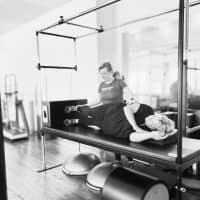 Woman adjusting a client in a Pilates class